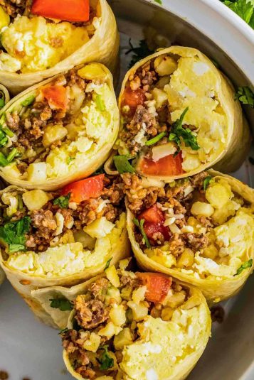 Six breakfast burrito halves placed in a large bowl, cut facing the camera.