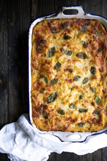 A lasagna made with butternut squash, zucchini, spinach and cheeses in a large casserole dish.