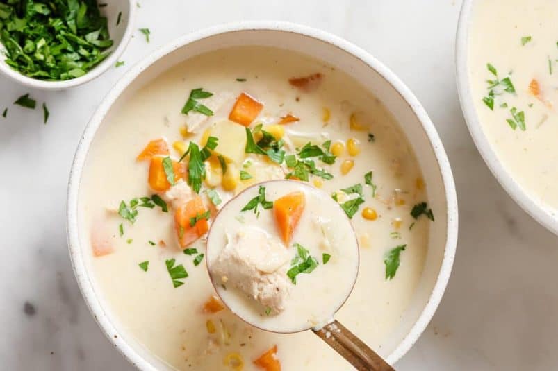 A white skillet of creamy garlic chicken garnished with herbs.