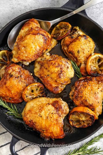 Skillet of Skillet Chicken Thighs with one on a spoon.