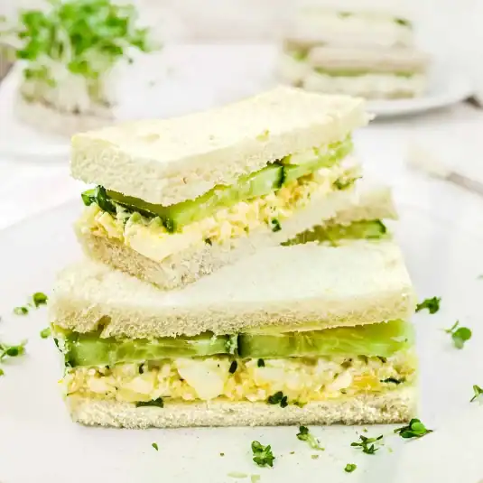 A bowl of mexican pinto beans topped with sliced avocado, a spoonful of plain yogurt, pickled red onions, and a wedge of lime.