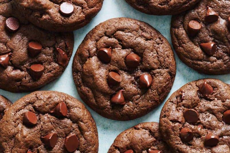 Overhead view of double chocolate chip cookies on a blue background.