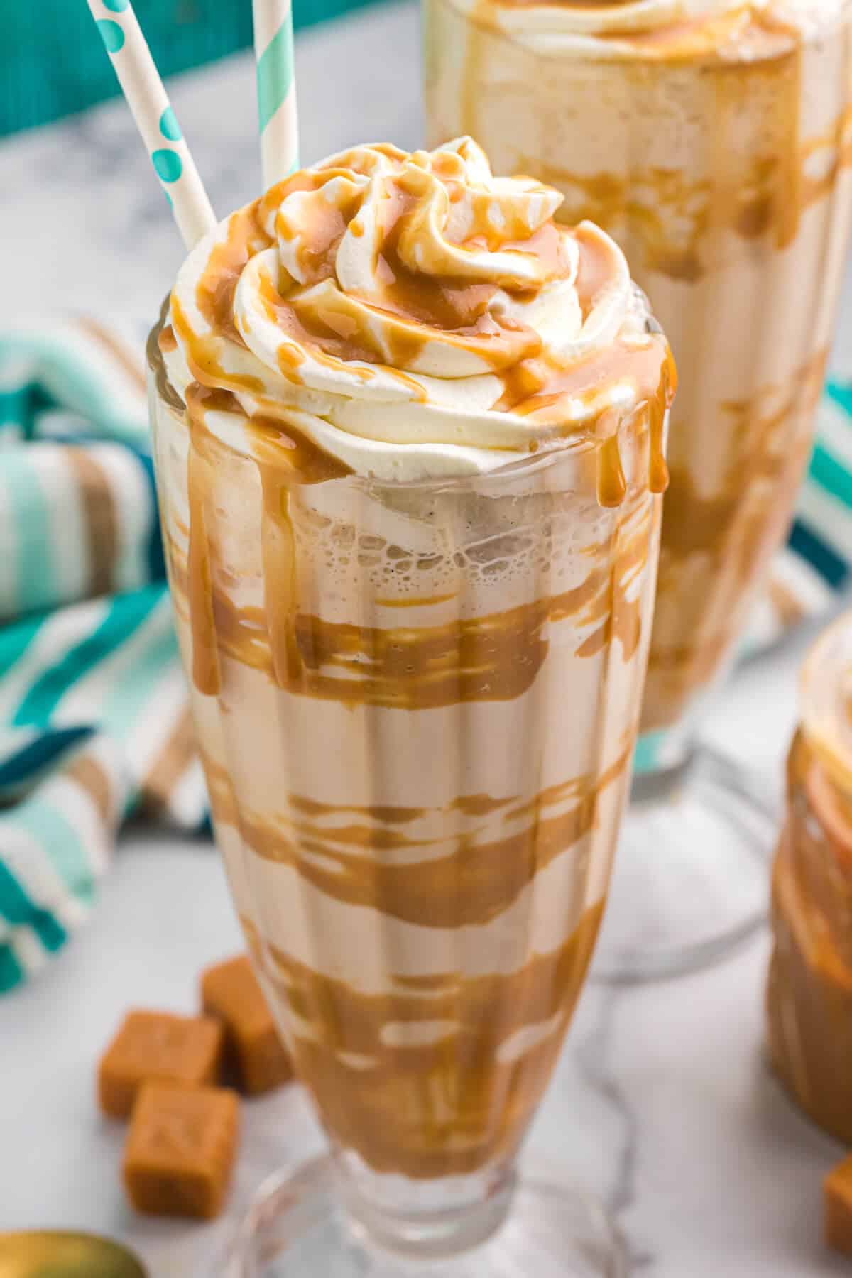 Two glasses filled with sweet caramel and fluffy whipped cream.