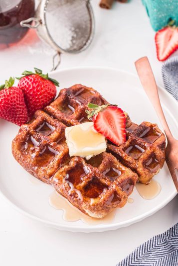 Waffles topped with butter and fresh strawberries.