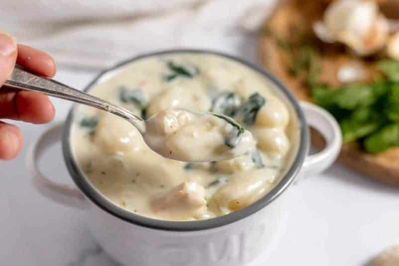 Soft dumplings in a white bowl with chicken and black pepper.