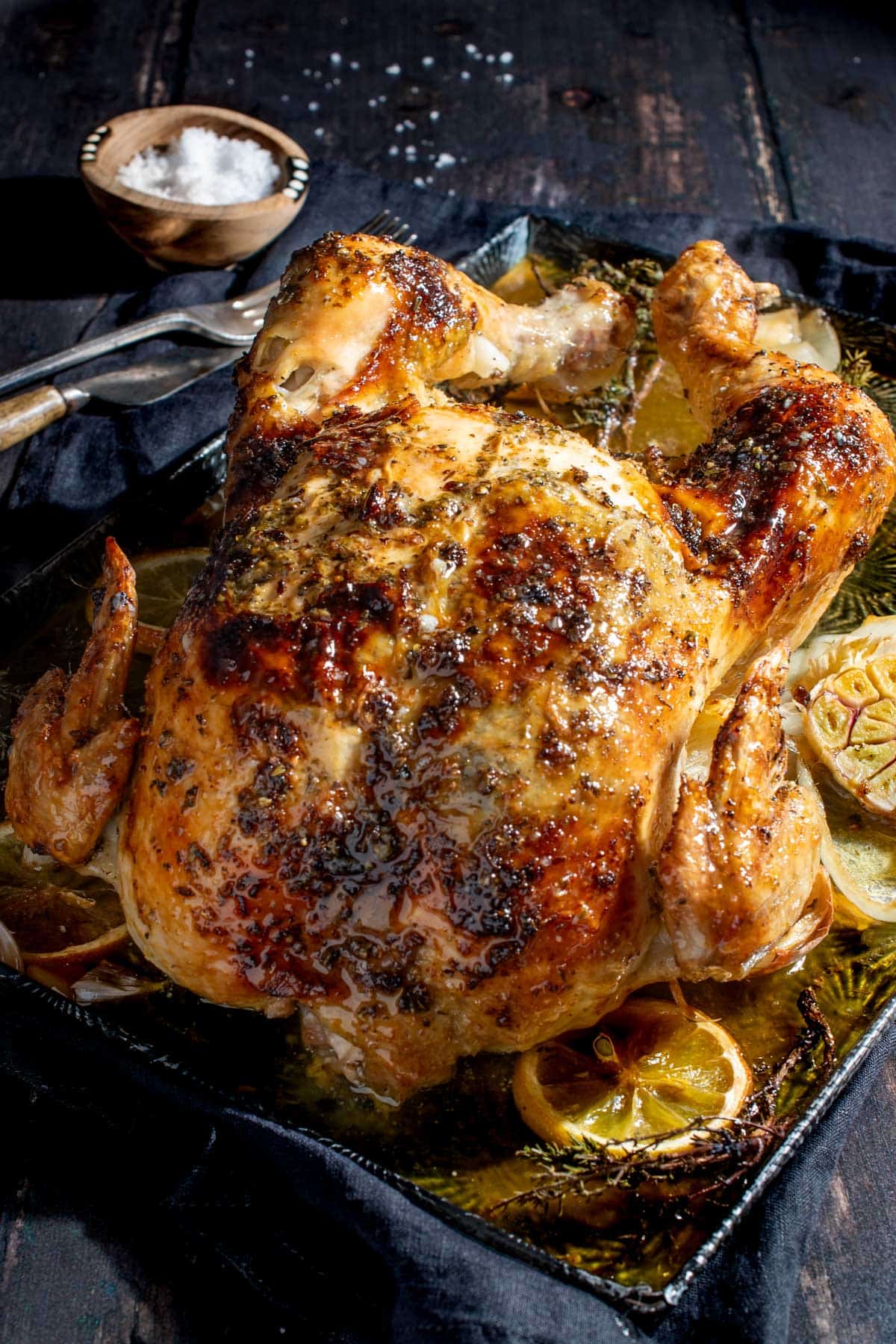 Whole Greek roast chicken on a baking tray.