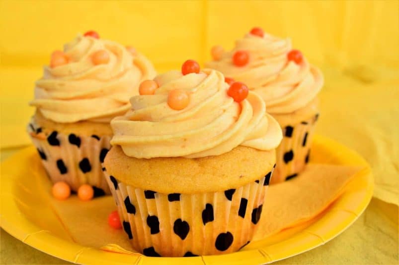 Pumpkin cupcakes on yellow plate.