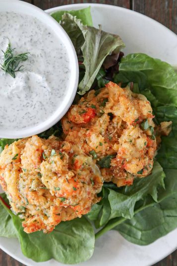 Two lobster cakes on a bed of spring greens with lemon dill sauce.