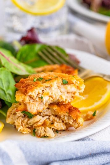 Close up of layered Crab Cake Recipe on plate with salad and dipping sauce.