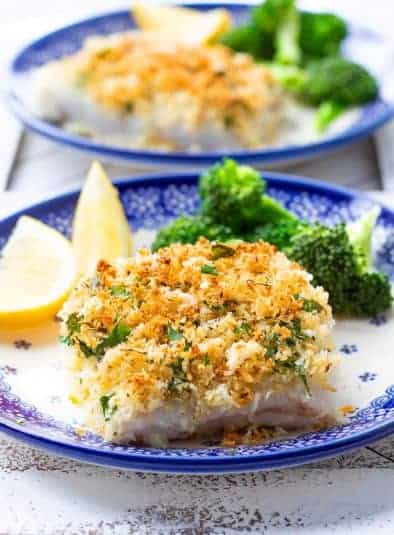 Parmesan crusted cod on plate with broccoli and lemon.