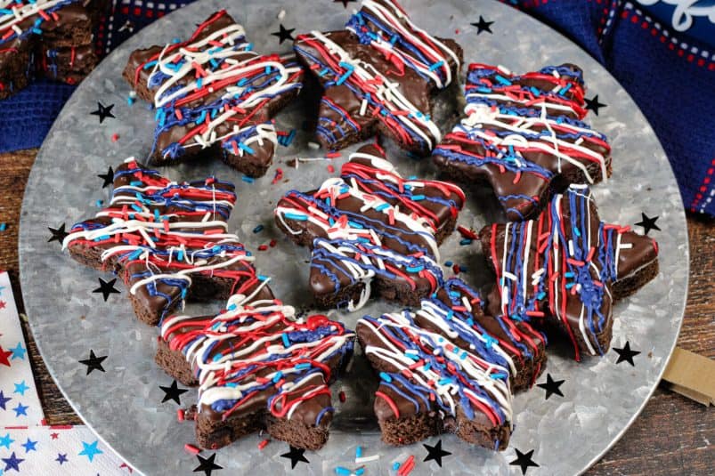 Patriotic star brownie with red white and blue drizzles and sprinkles on a galvanized platter with stars.