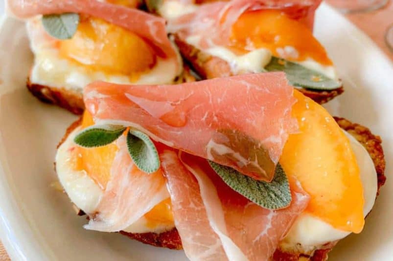 A stack of three golden-brown, flaky biscuits on a white surface, with a blurry background.