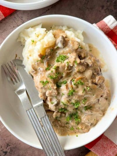A hand holding a piece of fried chicken.