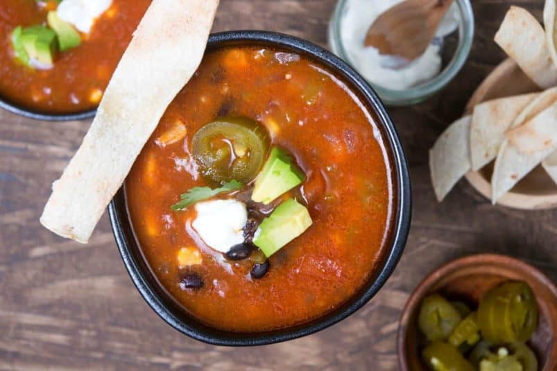 Mexican soup in black bowls with tortilla strips.