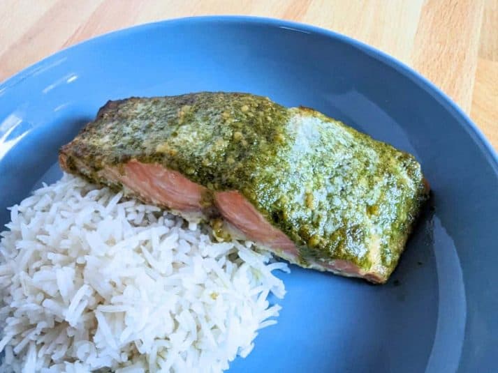 Image shows Salmon with pesto and rice on a blue plate.