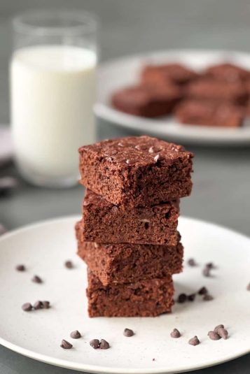 Banana brownies stalked on top one another on a serving plate with some chocolate chips.