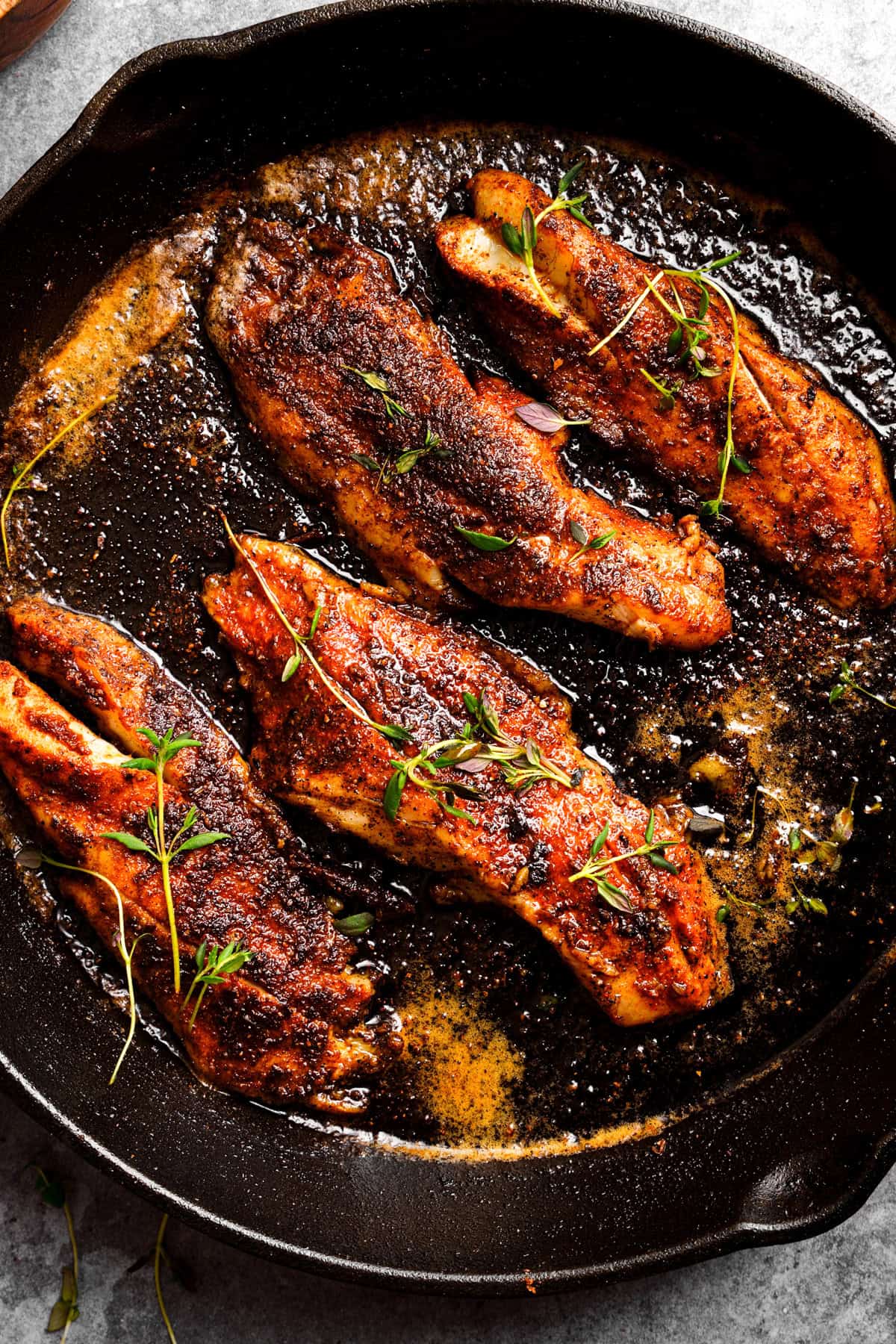 Close up of the blackened sea trout recipe with fresh thyme as a garnish.