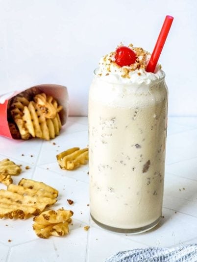 A tall glass filled with a thick, creamy caramel-colored milkshake. 