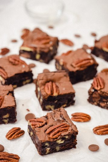 Pecan brownies cut into squares with scattered pecans and chocolate chips.