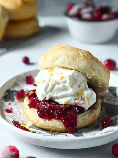 Cranberry shortcake on a biscuit with whipped cream on a white plate.