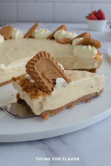 Close up image of a slice of lotus biscoff cheesecake on a white round plate.