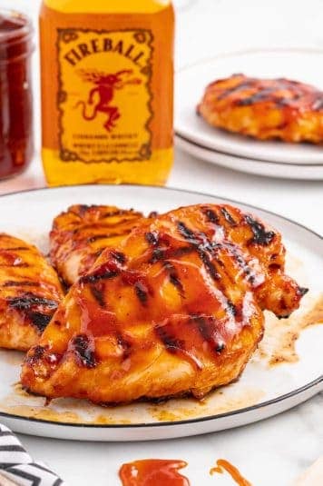 Grilled chicken with BBQ sauce and a bottle of whiskey.
