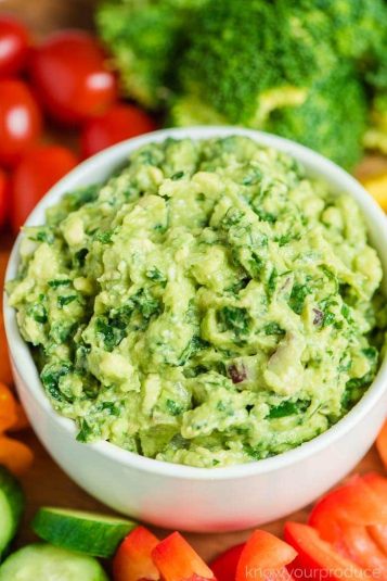 Kale guacamole in a bowl with veggie platter.