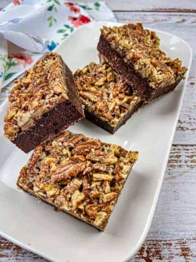 A plate of chocolate cookies with walnuts and chocolate pieces on the side.