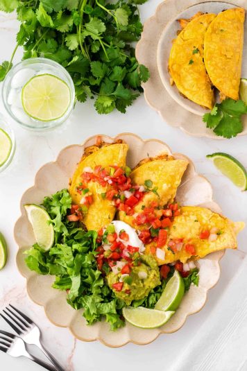 Three crispy chicken tacos served with lettuce, tomato and sour cream.