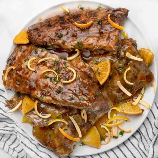 Racks of Chinese sticky ribs on a white platter.