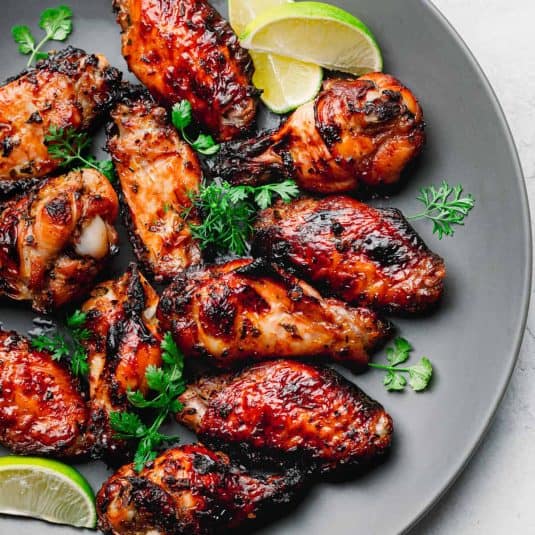 Grilled chicken wings garnished with herbs and lime.