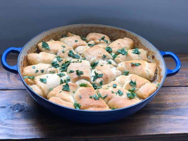 Pot of cheesy meat bake in the oven pan on a wooden table.