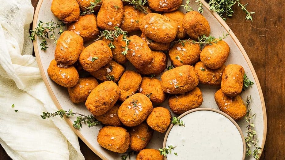 A plate full of sweet potato tater tots with dip.