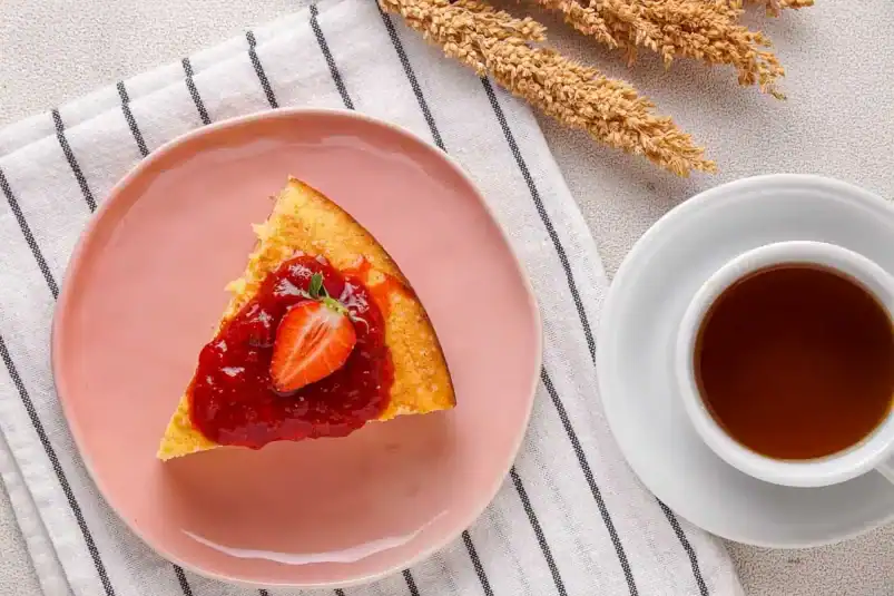 A top down view of a slice of cottage cheese cheesecake next to a cup of coffee.