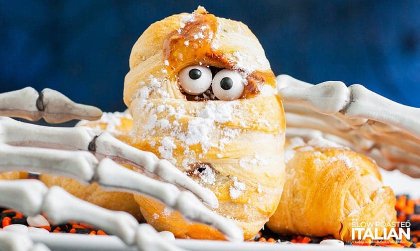 A hand holding a pastry covered in powdered sugar.