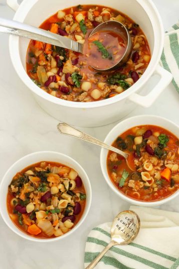 Two bowls and a soup pot of ground turkey soup.A green and white striped napkin with a spoon that says Crave Something Healthy is in the foreground.