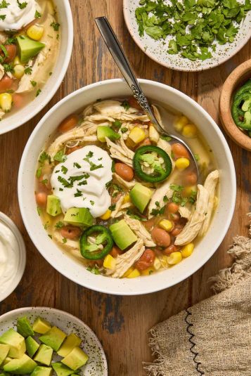 Crock Pot Green Enchilada Chicken Soup in a bowl with toppings.