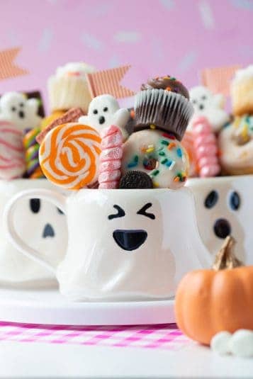 Ghost mugs filled with sweet treats and candies.
