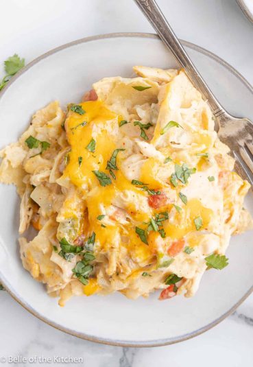 King ranch chicken casserole on a white plate with a fork next to it.