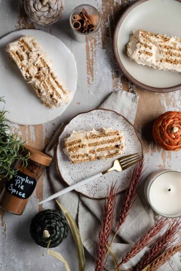 Three slices of pumpkin spice icebox cake are surrounded by pumpkin pie spice and sprigs of wheat.