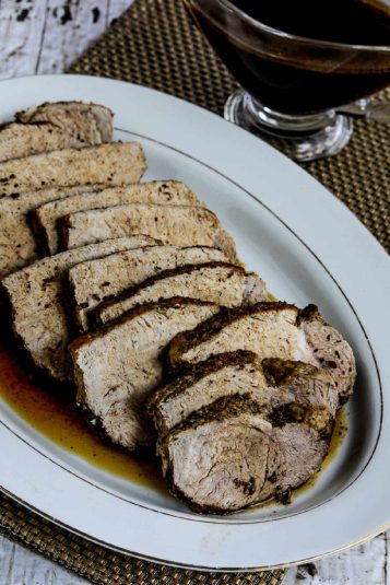 Instant Pot Balsamic Pork Roast on serving platter with formal napkin and sauce boat in background.