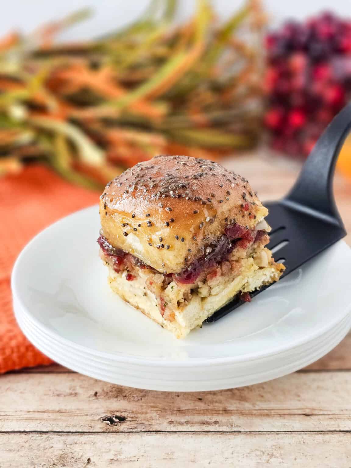 Cranberry turkey sliders with Hawaiian rolls on black spatula.