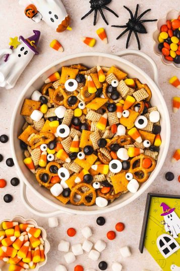 Top-down view of Halloween snack mix with candy corn, mini marshmallows, and candy eyes in a ceramic bowl.