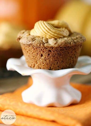 A white cake stand displaying delicious pumpkin spice muffin.