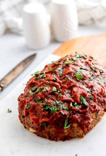 Baked 5 ingredient meatloaf resting on a cutting board before being sliced.