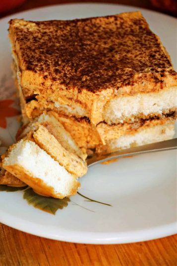 A slice of pumpkin tiramisu on a plate with a bite of tiramisu on a fork.