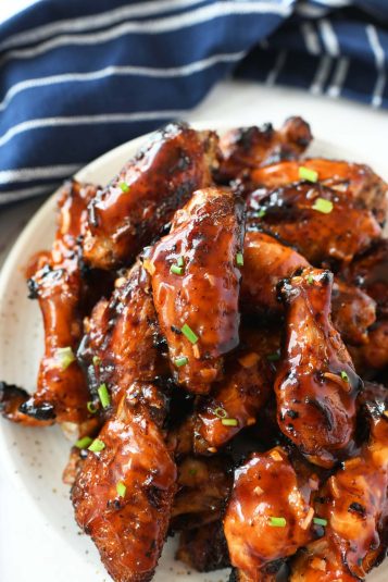 Apricot sticky chicken wings on a white plate with a blue napkin.