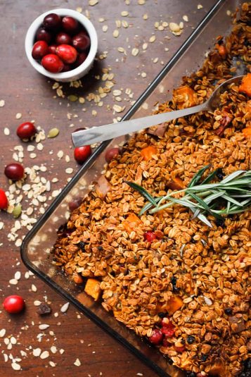 Hands holding paprika chicken and vegetables on a sheet pan.