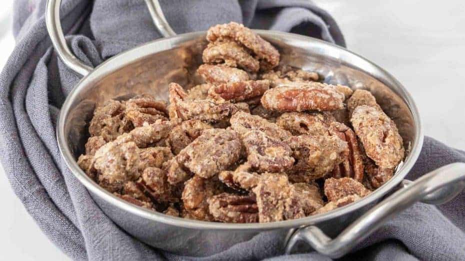 Glazed candied pecans spilling from a jar.