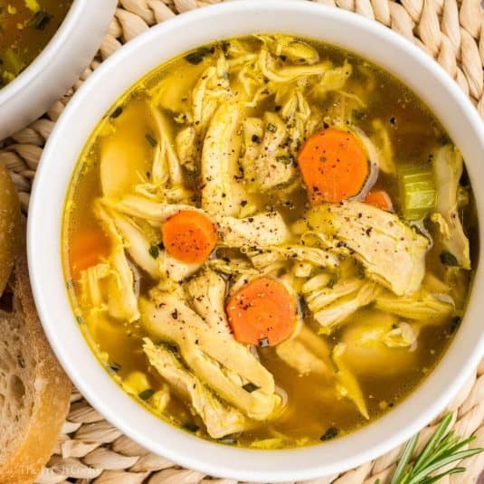 Bowl of chicken soup with crack pepper on top.